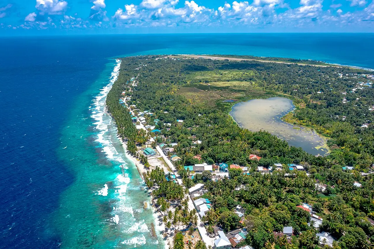Aerial view of Fuvahmulah showing its forested interior, an inland lake and the surf-washed reef edge