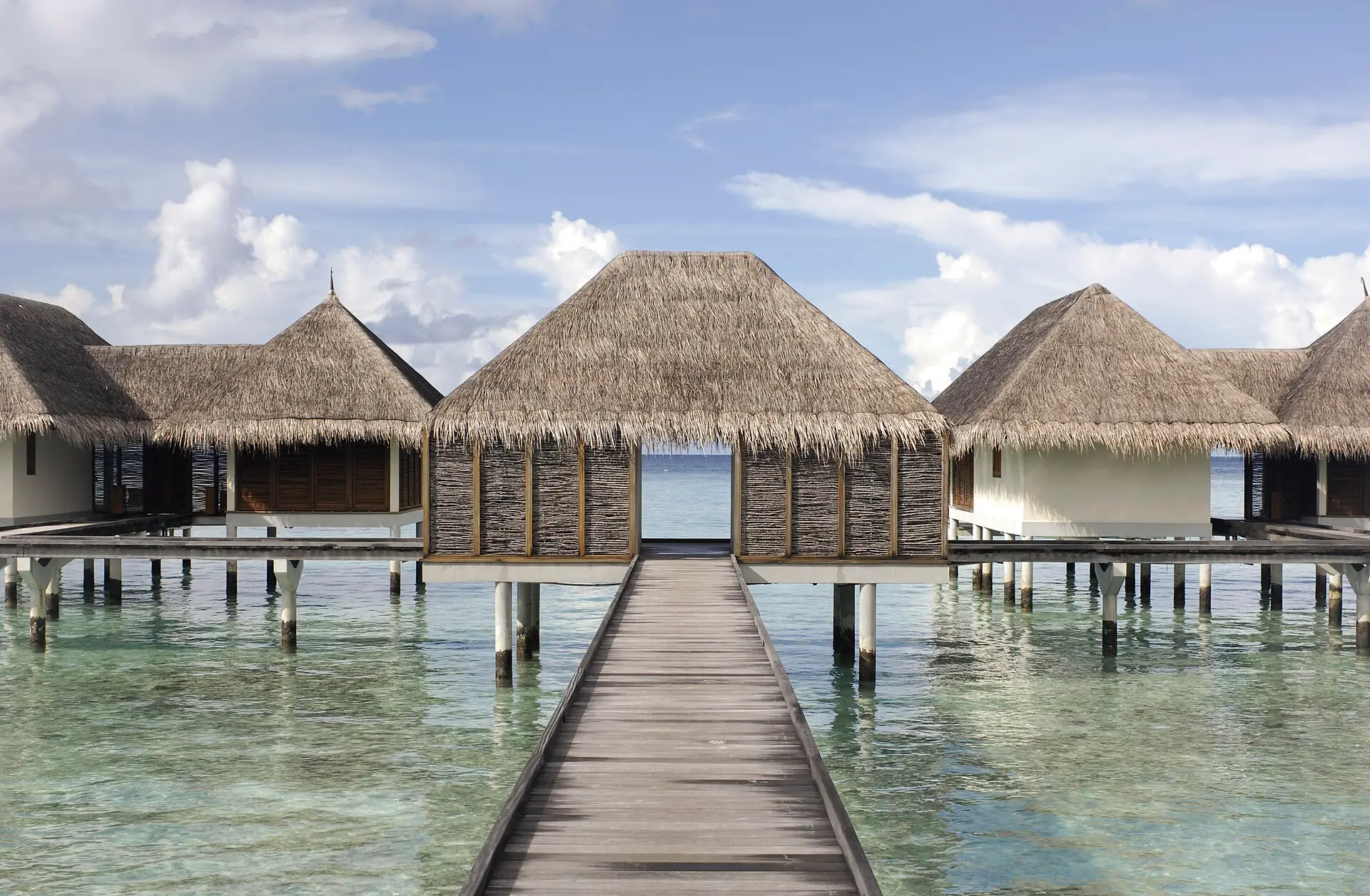 A wooden boardwalk leading to thatched-roof water villas at Landaa Giraavaru