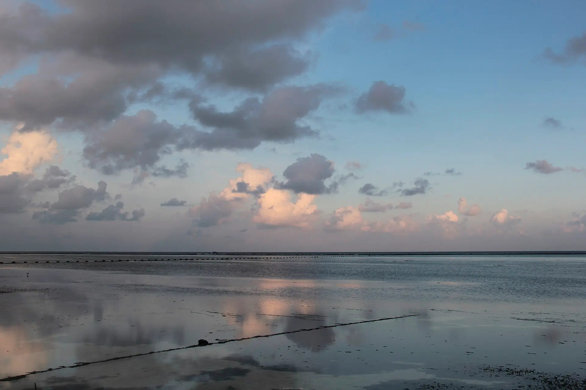 Calm, glassy shallows off Maafushi reflecting soft evening clouds over the Indian Ocean